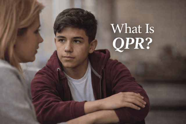 Teenage boy sitting indoors, listening attentively while a woman speaks to him and gently holds his arm, with text reading “What Is QPR?”